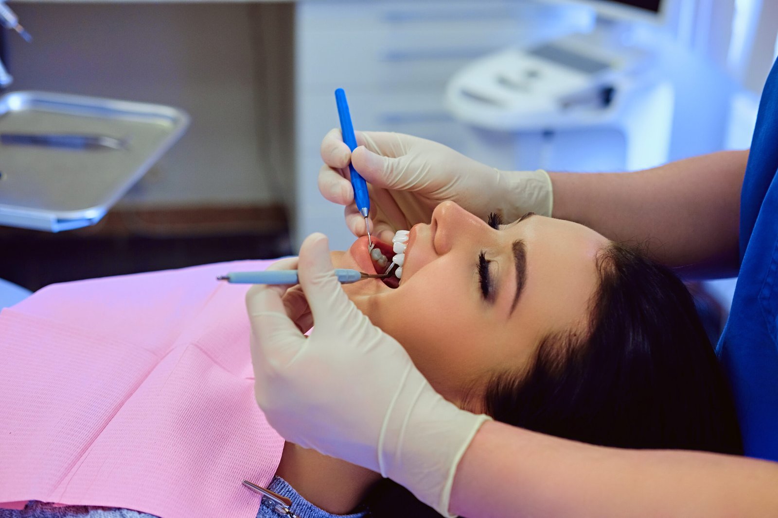 Dentist examining female's teeth in dentistry.